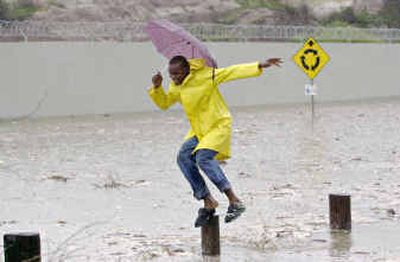 
A Jamaican man jumps as he crosses a street Friday, flooded by the first rains of Hurricane Ivan, which is approaching Kingston, Jamaica.
 (Associated Press / The Spokesman-Review)