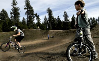 Five-year-old Mason Crabtree, of Coeur d’Alene, watches as Ashton Palmer, 17, makes his way around the BMX track at Cherry Hill Park  on April 6.  (Kathy Plonka / The Spokesman-Review)