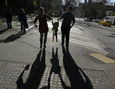 In this March 3, 2015, file photo, a child is lifted by her parents at a street corner in downtown Seattle. The expansion of a child tax credit helped seal Congress’ approval of the Republican tax overhaul, but it might not be as helpful to lower-income families as it was portrayed. (Ted S. Warren / Associated Press)