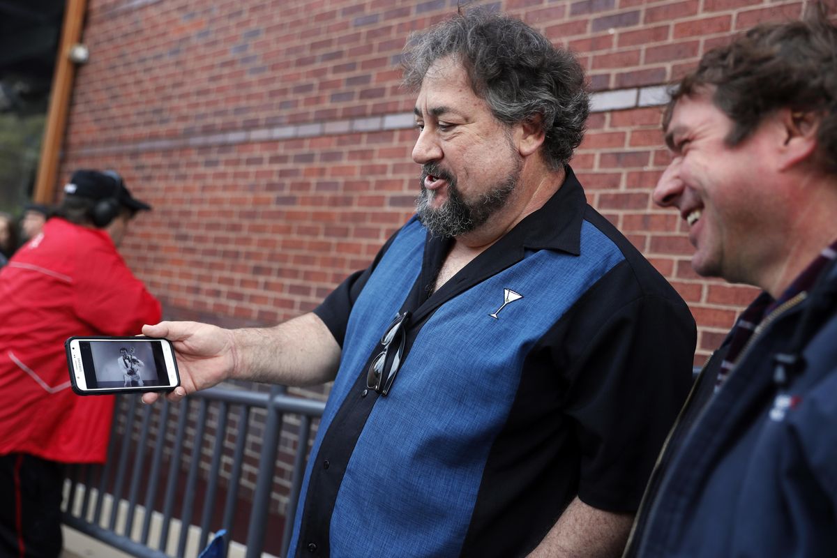 Alan Bozich, left, holds up his phone to watch a video of Chuck Berry as he stands in line with Jimmy Herrmann, right, to pay their respects to the rock 