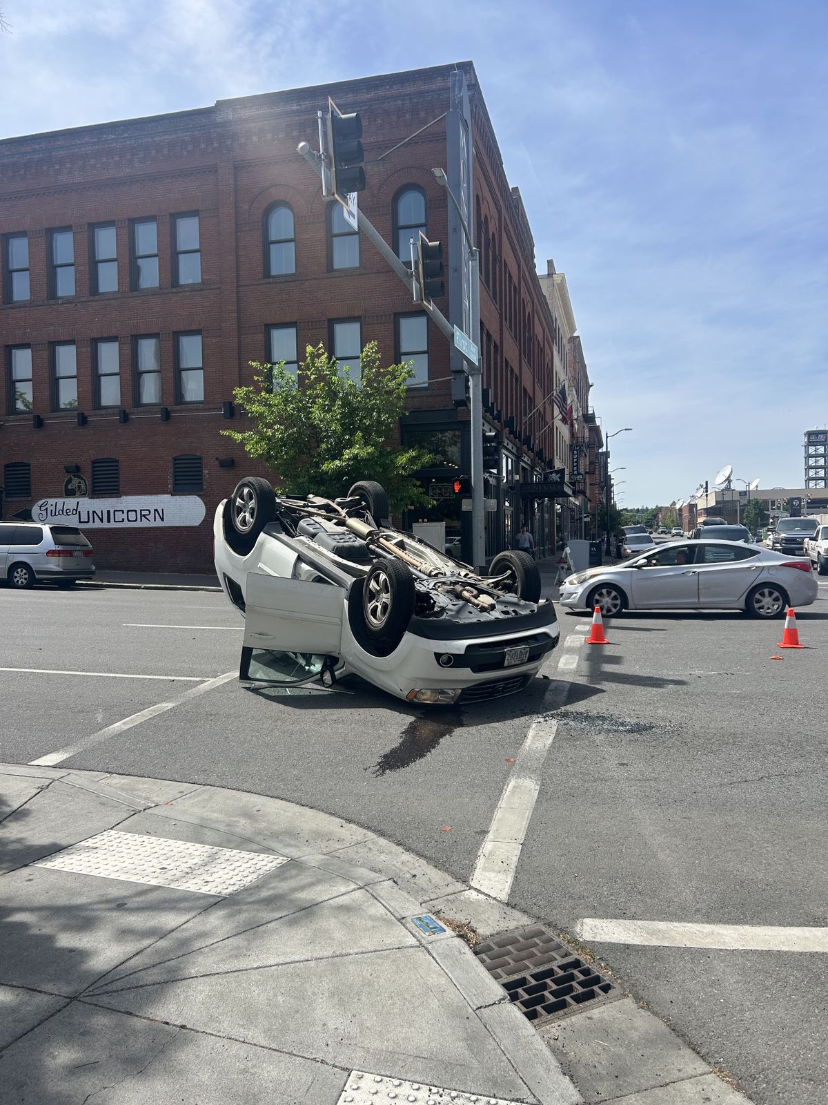 A white Honda Pilot is flipped on its back at the intersection of Monroe Street and First Avenue on Tuesday afternoon in downtown Spokane.  (Mathew Callaghan / The Spokesman-Review)