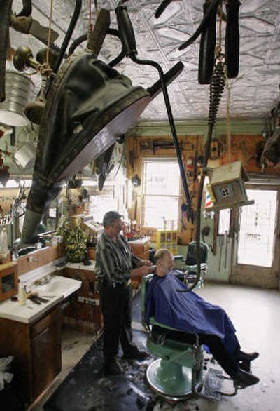 
Associated Press  Articles hang from the ceiling at Red's Barbershop in Mattoon, Ill.,  as John Romack gets his hair cut by Jerry McDaniels. Mattoon is one of four towns competitn to be the site of a coal to gas plant
 (Associated Press / The Spokesman-Review)