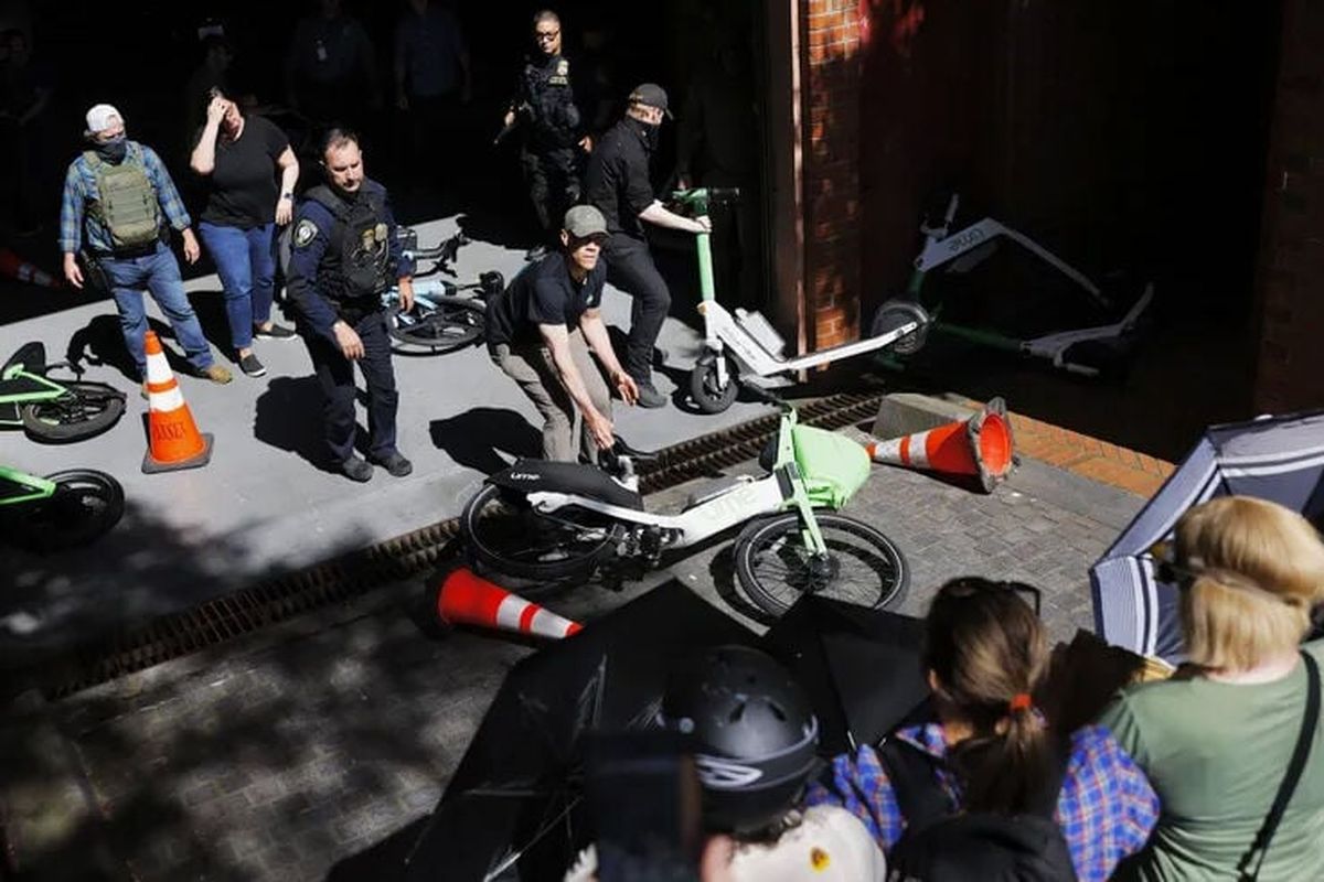 Federal officers pull scooters and bikes inside the sally port of the Henry M. Jackson Federal Building as protesters block the driveway Tuesday in Seattle. (Nick Wagner/Seattle Times)