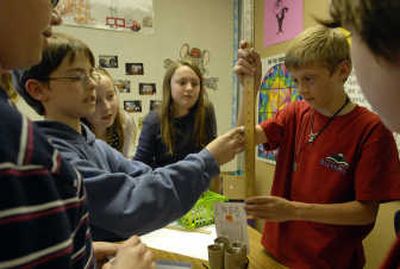 
Summit School fifth-graders in the Able Learners program, from left, Evan Oeflein, Emily Peters and Natalie Harrington, watch as Brian Choate uses a yard stick to measure how far dominoes drop to solve a problem they created called domino towers.
 (J. BART RAYNIAK / The Spokesman-Review)