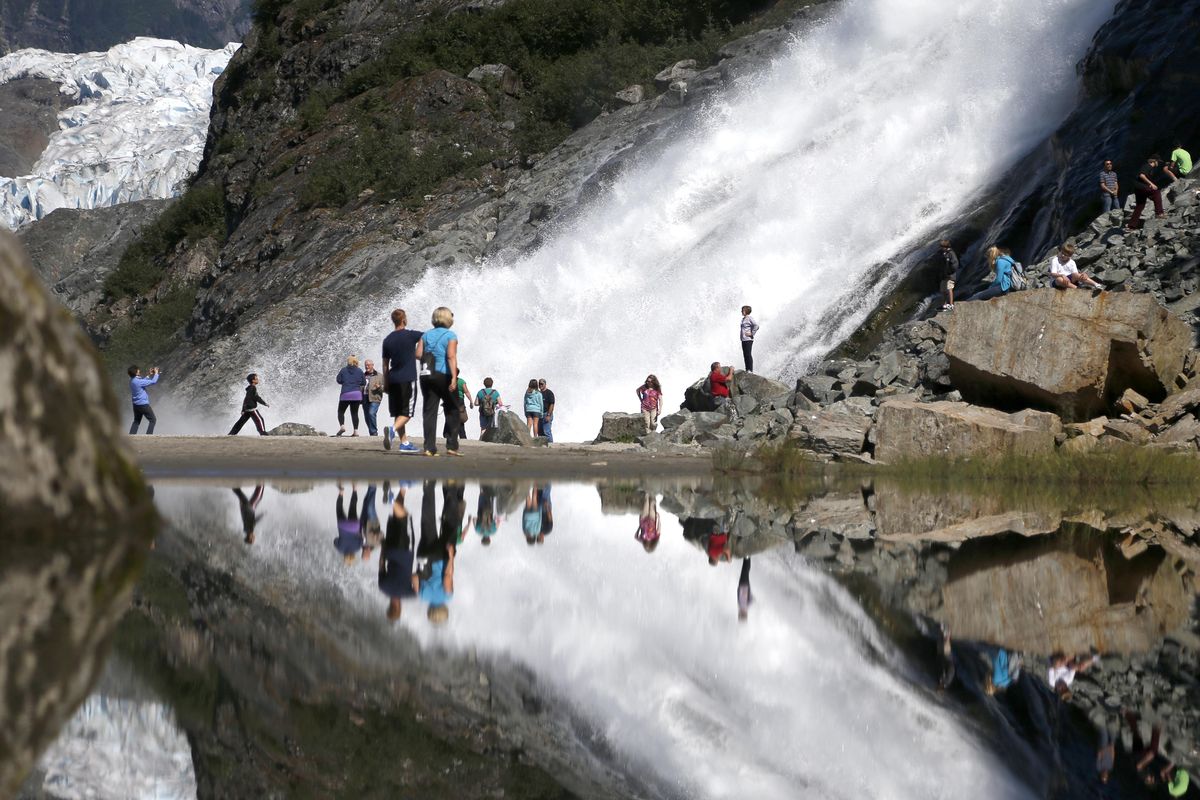 Tourists visiting the Mendenhall Glacier in the Tongass National Forest are reflected in a pool of water July 31, 2013, as they make their way to Nugget Falls in Juneau, Alaska.  (Associated Press)