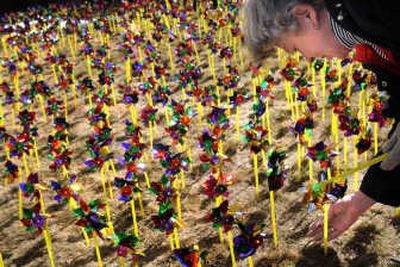 
Bess Pope helps plant pinwheels Wednesday at Vanessa Behan Crisis Nursery in Spokane. Volunteers set up a pinwheel for each child who came to the nursery last year.
 (Rajah Bose / The Spokesman-Review)