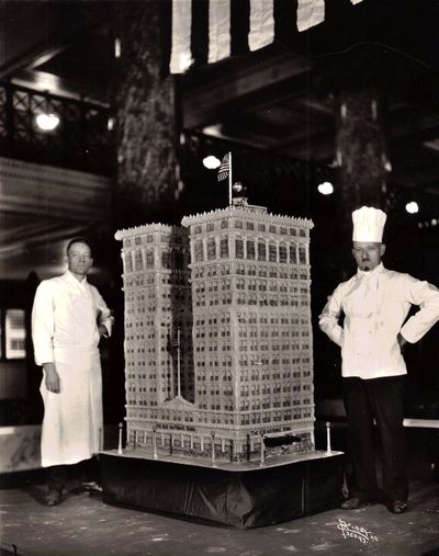 The article in the Spokane Daily Chronicle that accompanied this photo explained that the Money Cake weighed 1,100 pounds. It was designed and baked by chefs at the Davenport Hotel and was as tall as the chefs who made it.