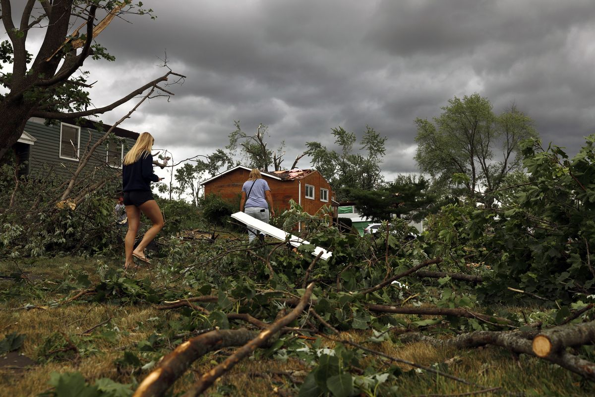 Residents walk past damaged houses and fallen trees after a tornado passed through the area on Monday, June 21, 2021 in Woodridge, Ill.  (Shafkat Anowar)