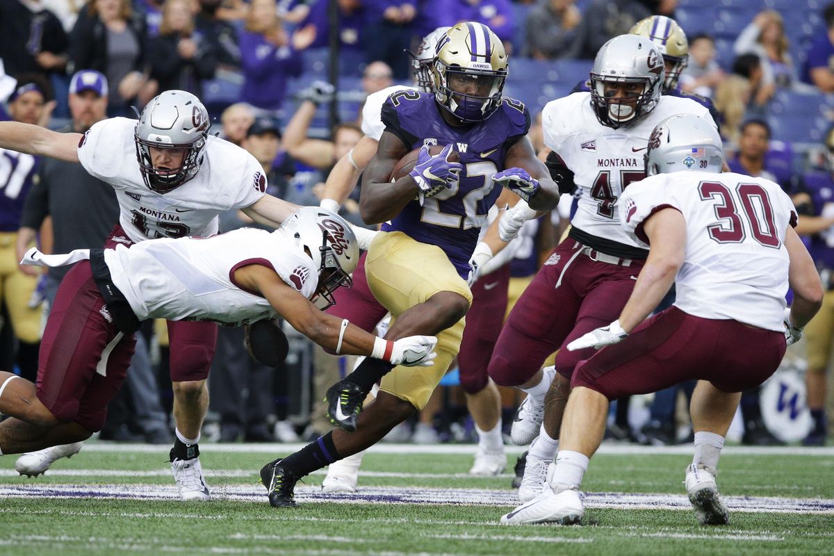 Washington running back Lavon Coleman (22) avoids a diving tackle attempt from Montana safety Justin Strong, lower left, as he rushes in the first half of an NCAA college football game, Saturday, Sept. 9, 2017, in Seattle. (Ted S. Warren / Associated Press)