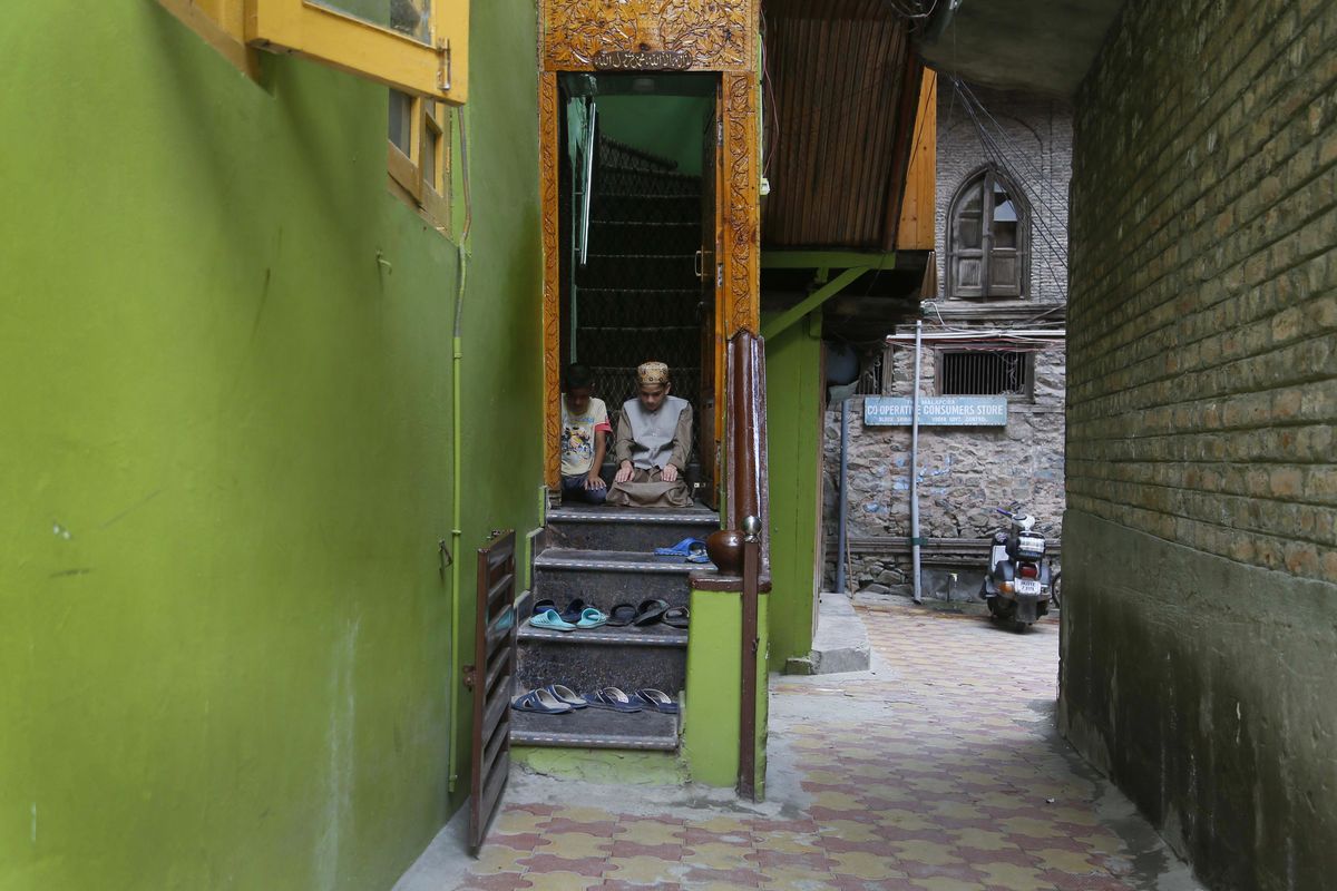 Kashmiri Muslim boys offer Friday prayers at the doorway of a local mosque in an alley during curfew like restrictions in Srinagar, India, Friday, Aug. 16, 2019. India’s government assured the Supreme Court on Friday  the situation in disputed Kashmir is being reviewed daily and unprecedented security restrictions will be removed over the next few days, an attorney said after the court heard challenges to India’s moves. (Mukhtar Khan / Associated Press)