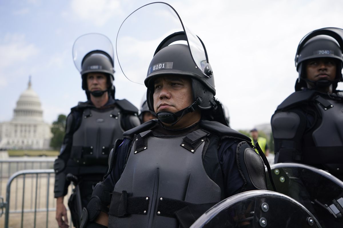 Police in riot gear patrol as people attend a rally near the U.S. Capitol in Washington, Saturday, Sept. 18, 2021. The rally was planned by allies of former President Donald Trump and aimed at supporting the so-called "political prisoners" of the Jan. 6 insurrection at the U.S. Capitol.  (Brynn Anderson)