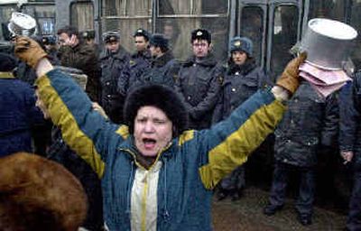 
A woman waves saucepans as she protests in front of police officers in downtown St. Petersburg on Monday. 
 (Associated Press / The Spokesman-Review)