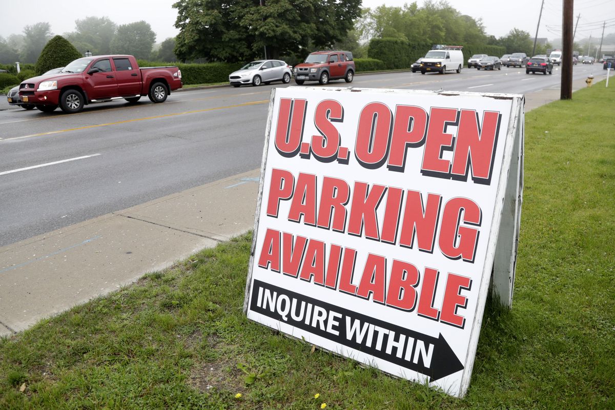 A sign for parking is displayed in front of a private lot as vehicles drive slowly in traffic along County Road 39 near the site of the U.S. Open Golf Championship on Wednesday in Southampton, New York. (Julio Cortez / AP)