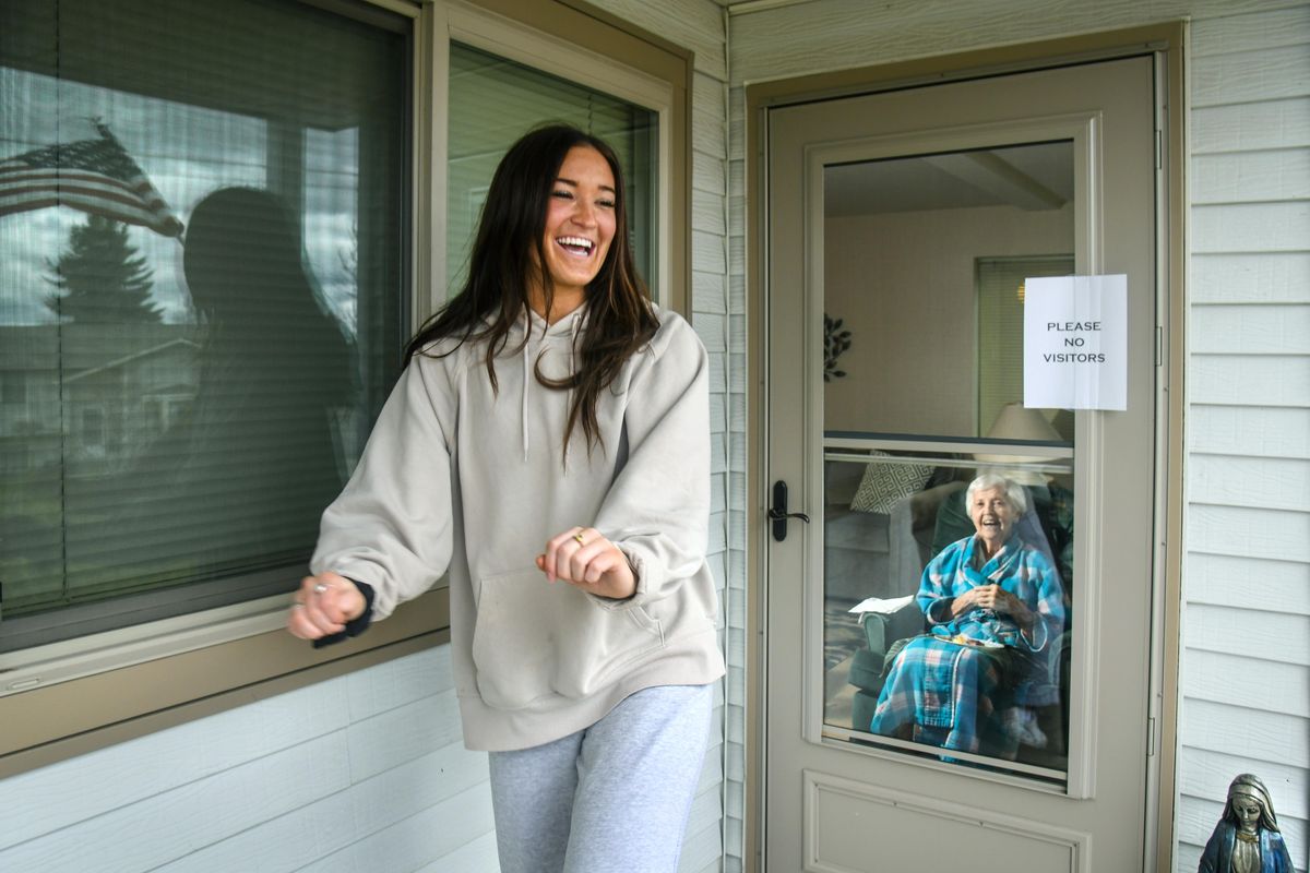 University of Washington student Michaela Laabs, 20, spent a late breakfast visiting and showing off her TikTok dance moves to her grandmother, Connie Laabs, 88, through the doorway at Holman Gardens Retirement Community, Friday, April 3, 2020, in Spokane Valley. The pair, separated because of COVID-19 concerns, try and get together twice a week to tell jokes, talk about dancing and Connie’s younger days. (Dan Pelle / The Spokesman-Review)