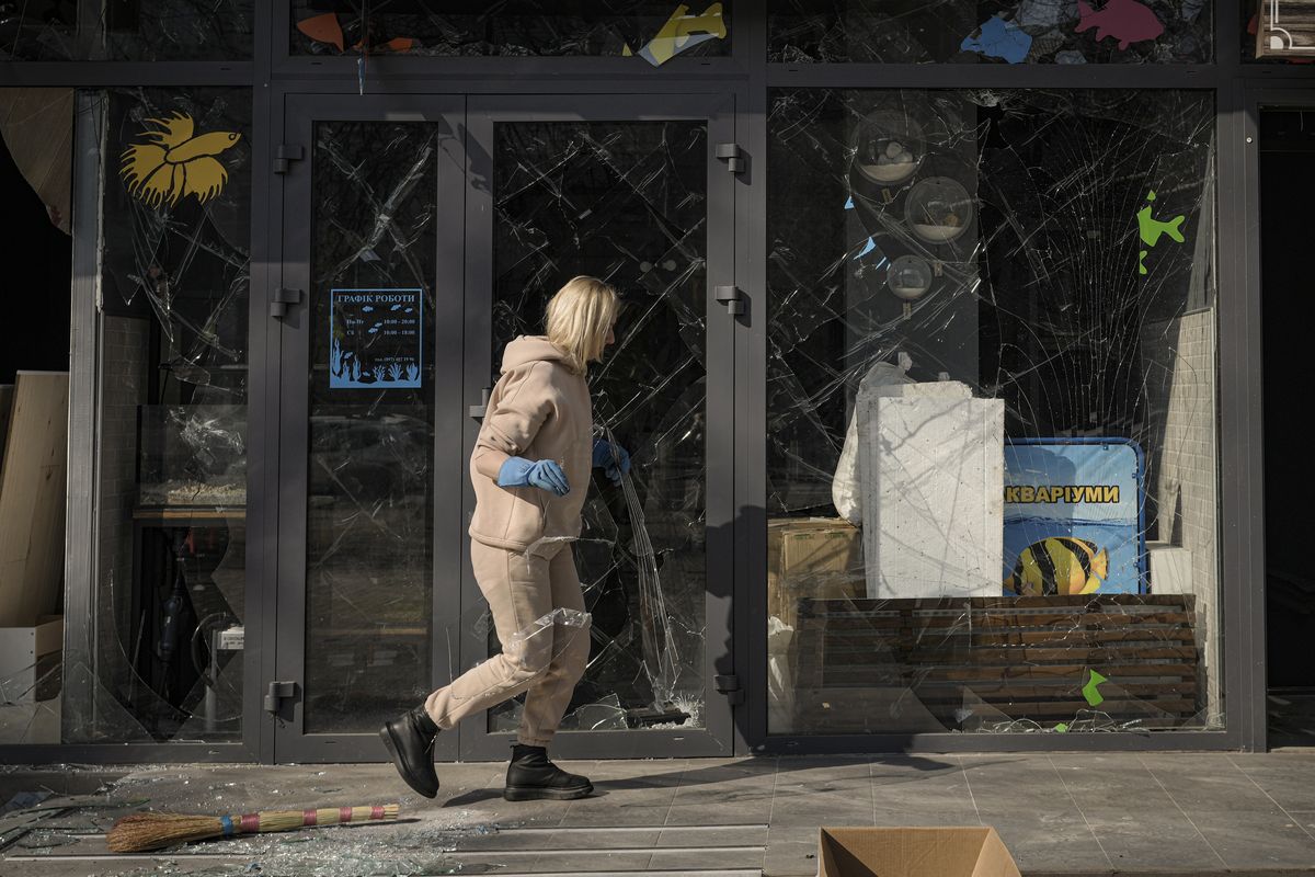FILE - A woman removes pieces of broken glass from a shop window after a bombing in Kyiv, Ukraine, Wednesday, March 23, 2022. The World Bank said Sunday, April 10, 2022 that Ukraine