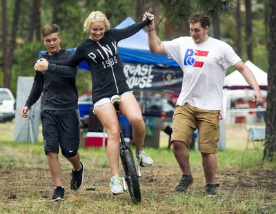 Melissa Wheeler, with the help of her son Daetyn Wheeler, 13, left, and Phil Sanders, learns to ride a unicycle at the Spokatopia Outdoor Adventure Festival held Saturday at Camp Sekani on Upriver Drive. (Colin Mulvany)