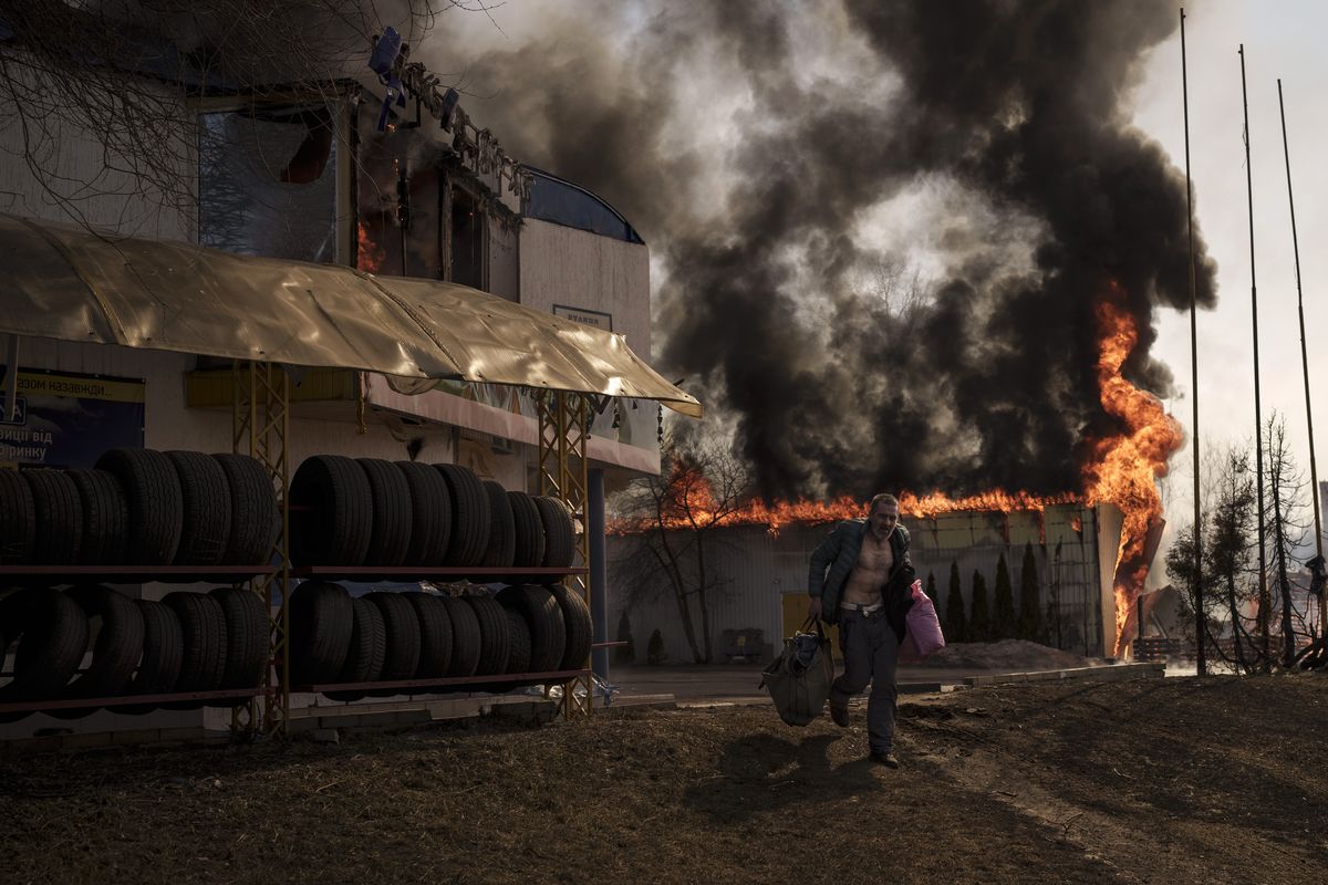 A man recovers items from a burning shop following a Russian attack in Kharkiv, Ukraine, Friday, March 25, 2022.  (Felipe Dana)