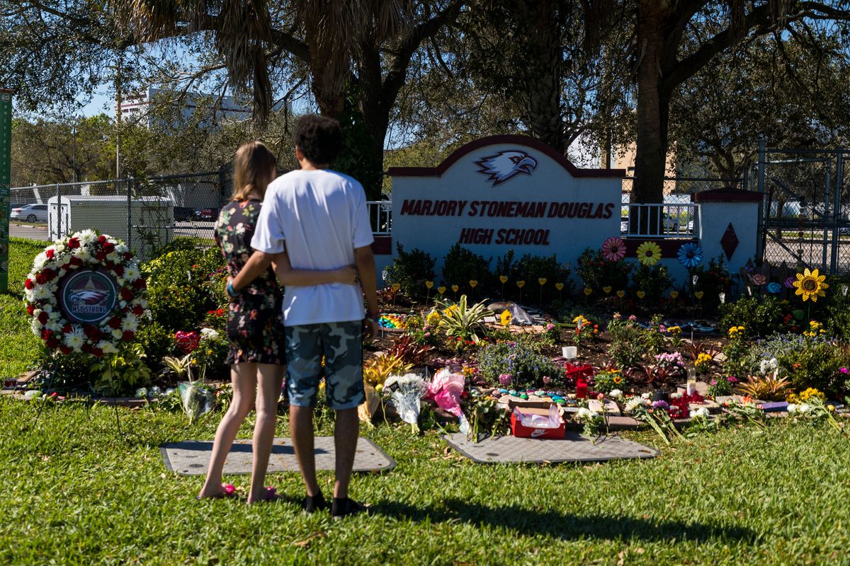 Two people embrace at a memorial at Marjory Stoneman Douglas High School to honor those killed on the fifth anniversary of the mass shooting on Feb. 14 in Parkland, Fla. On Feb. 14, 2018, 14 students and three staff members were killed during the shooting at the school.  (Saul Martinez)