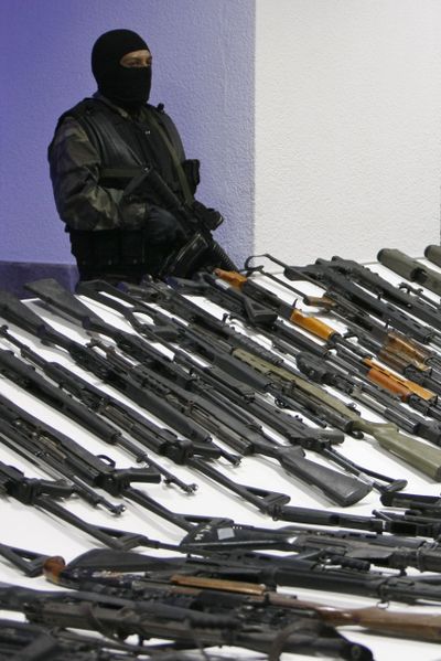 A Mexican soldier stands guard Friday over   weapons captured in an operation against the Gulf drug cartel.  (Associated Press / The Spokesman-Review)