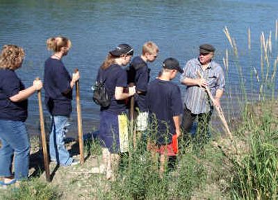
Rod Erickson, right, owner of the Fireside in the town of Spirt Lake, teaches a group of young volunteers how to find leaks around the Mill Pond area.
 (Paula Davenport / The Spokesman-Review)