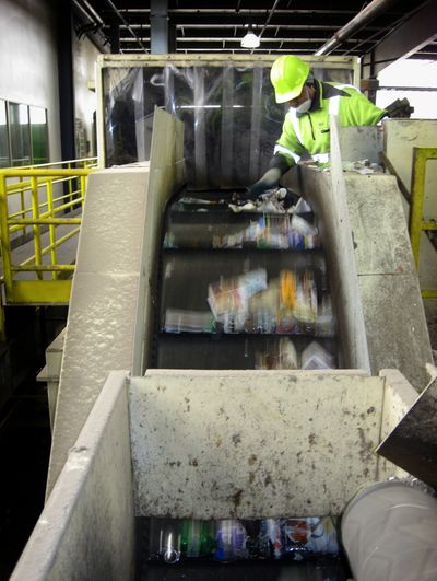 Hailu Aiemu removes material unsuitable for recycling as the sorting process begins at the Waste Management  plant in Woodinville, Wash. (Bert  Caldwell)