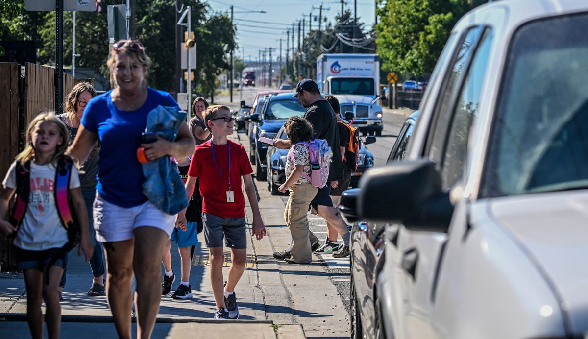 Students and parents make their way through lines of traffic during pick-up time Sept. 4 at Seth Woodard Elementary School.  (Kathy Plonka/The Spokesman-Review)