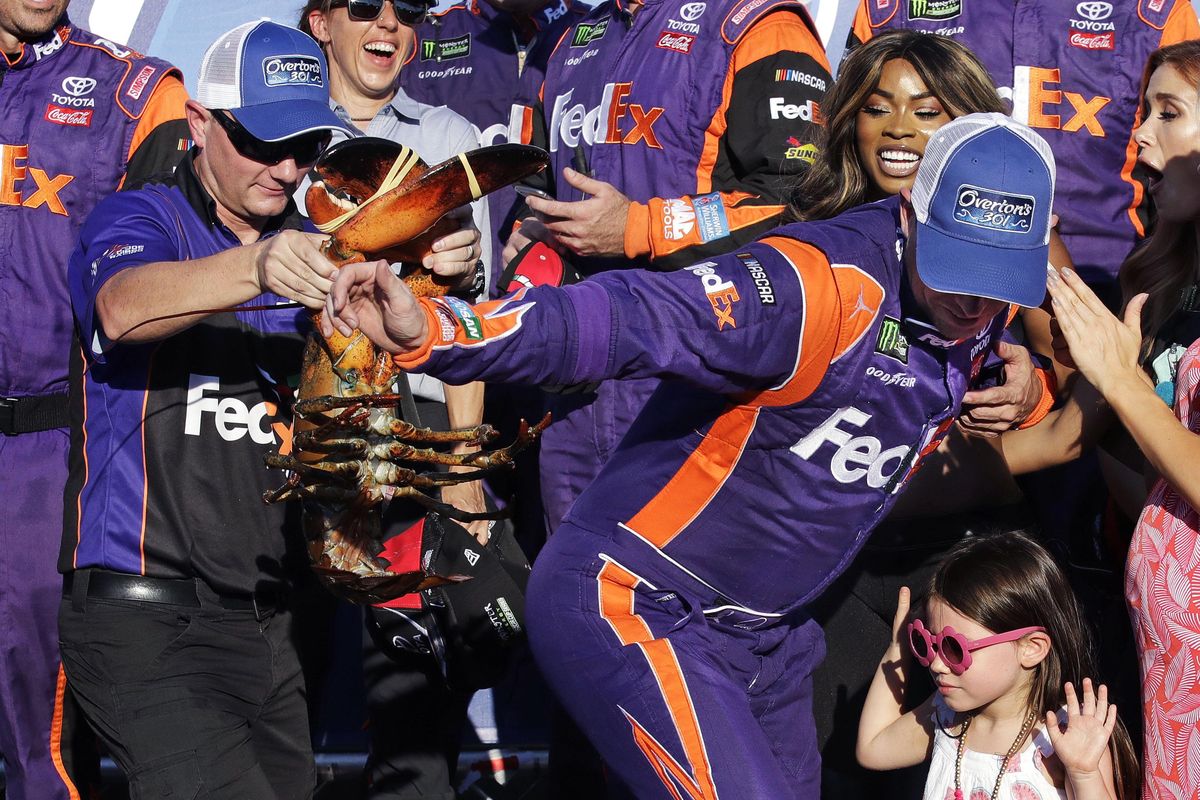 Driver Denny Hamlin, right, is chased by a crew member holding a lobster after winning the NASCAR Cup Series 301 auto race at New Hampshire Motor Speedway in Loudon, N.H., Sunday, July 16, 2017. (Charles Krupa / Associated Press)
