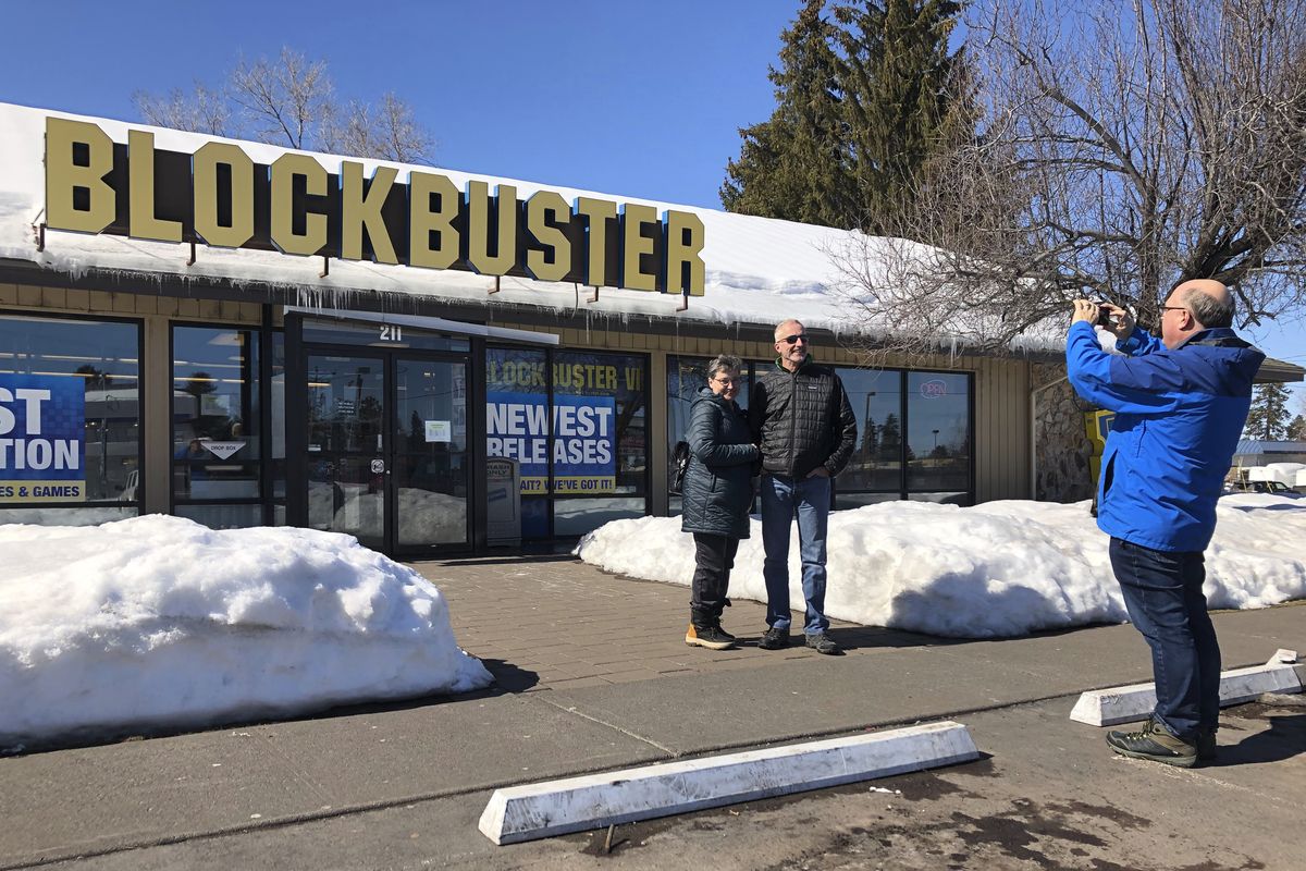 Debby Saltzman, of Bend, Ore., poses for a photo in March 2019 in front of the last Blockbuster store with her twin brother, Michael, visiting from Melbourne, Australia, in Bend, Ore.  (Gillian Flaccus)
