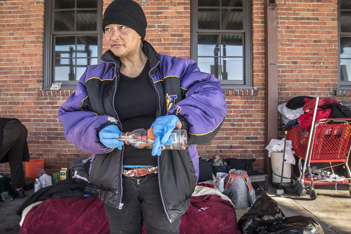 Jonita “Pink” Chavez shows a sports drink bottle containing used syringes she gathered from around the Tinbender Craft Distillery building. Chavez makes a point of picking up the litter and garbage around her bed outside the Tinbender, where she has made her home for the past few weeks. The needles are not hers. (Dan Pelle / The Spokesman-Review)