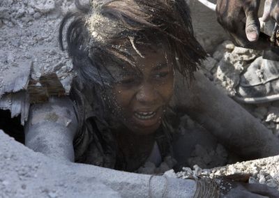 A survivor climbs out from under the rubble of a school after it collapsed during classes on Friday in Petionville, Haiti. About 500 students attended the school.  (Associated Press / The Spokesman-Review)