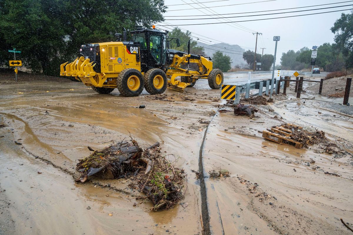 A road grader clears mud and debris along a closed E. Santiago Canyon Road at the intersection of Modjeska Canyon Road in eastern Orange County, Calif., as a winter storm brought heavy rain, high winds and flash flooding to Orange County and Southern California Tuesday, Dec. 14, 2021.  (Mark Rightmire)
