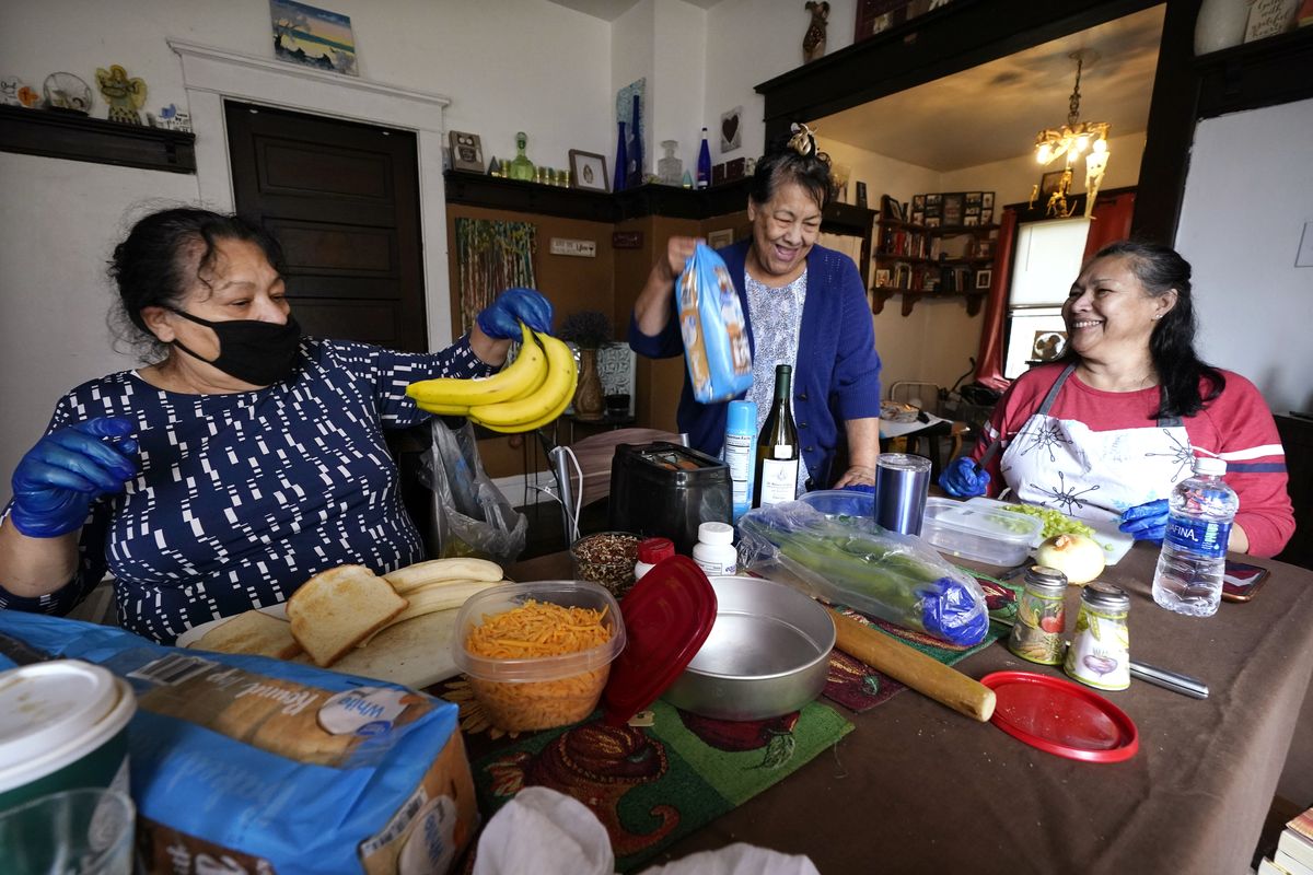 Olga Garcia, left, and her sisters Francis Garcia, center, and Anna Garcia work to prepare an afternoon family meal Wednesday, Nov. 4, 2020, in the family home in Sedro-Woolley, Wash. On any other Thanksgiving, dozens of Olga
