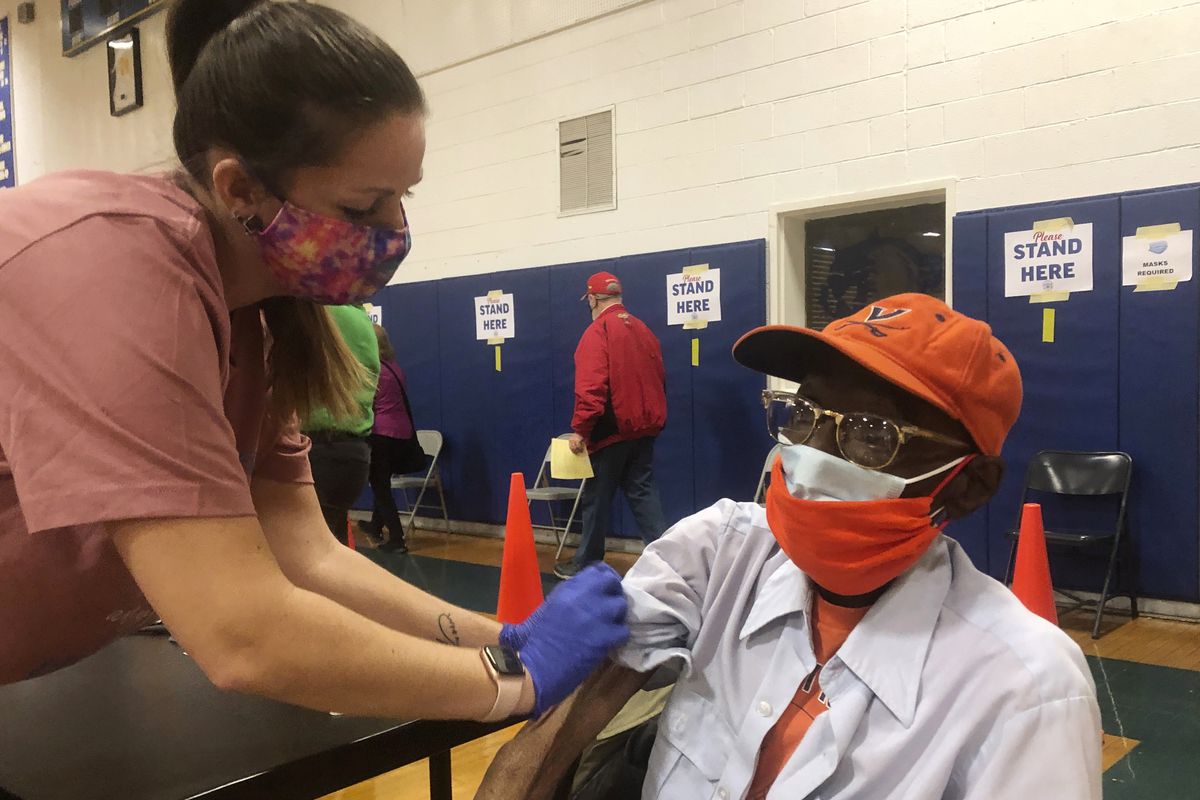 Debbie Monahan, a school nurse, pulls down Charles Robbins’ sleeve after giving him his second shot of the coronavirus vaccine Saturday at Surry County High School in Dendron, Va.. (Ben Finley)