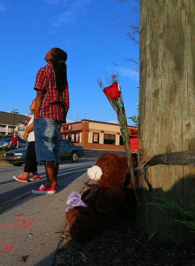 Local resident Ciara Edmonds glances up at telephone wires and lines after placing the rose at right on a shrine of the crash site where a police helicopter crashed killing two officers in Atlanta on Sunday, Nov. 4, 2012. The crash occurred Saturday during a search for a missing child. (Curtis Compton / Atlanta Journal & Constitution)