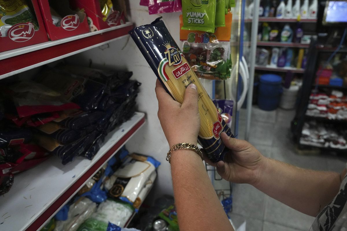 A man looks at a pack of pasta at a grocery store in Tehran, Iran, Wednesday, May 11, 2022. Iran abruptly raised prices as much as 300% for a variety of staples such as cooking oil, chicken, eggs and milk on Thursday.  (Vahid Salemi)