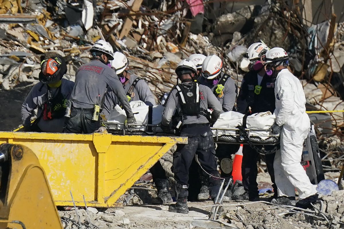 FILE - In this Friday, July 2, 2021, file photo, search and rescue personnel remove remains on a stretcher as they work atop the rubble of the Champlain Tower South complex in Surfside, Fla. Nobody has been found alive since the first hours of the June 24 disaster that killed at least 27 people in the town of Surfside, so updating the families has so far been a matter of delivering bad news. And what crews are finding is often not intact.  (Mark Humphrey)