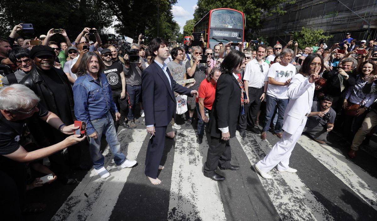 Fans dressed as lookalikes walk across the Abbey Road zebra crossing on the 50th anniversary of British pop musicians The Beatles doing it for their album cover of “Abbey Road” in St. John’s Wood in London, Thursday, Aug. 8, 2019. They aimed to cross 50 years to the minute since the “Fab Four” were photographed for the album. (Kirsty Wigglesworth / Associated Press)