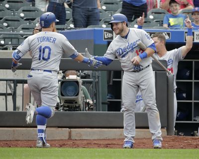 Los Angeles Dodgers’ Justin Turner is greeted by Max Muncy after hitting a solo home run during the 11th inning of  against the New York Mets Sunday at Citi Field. (Seth Wenig / AP)