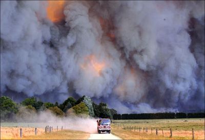 An emergency vehicle races away from a blaze near a structure in the Gippsland region in Australia’s Victoria state on Saturday.  Wildfires  killed at least 35 people and razed some 100 homes.  (Associated Press / The Spokesman-Review)