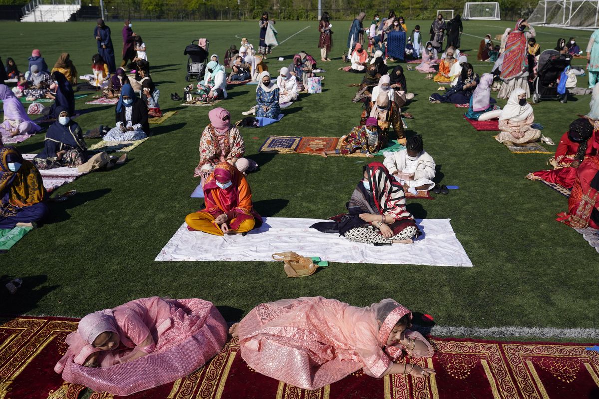 Aqsa Syeda, 8, left front, and her cousin Ameena Ahmed, 9, right front, relax before the start of Eid al-Fitr prayers on Thursday in Overpeck County Park in Ridgefield Park, N.J.  (Seth Wenig)