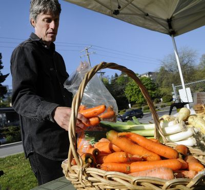 Tim Pellow, of Tolstoy Farms, sets out a selection of carrots on May 12 at the Spokane Farmers Market. (Dan Pelle)