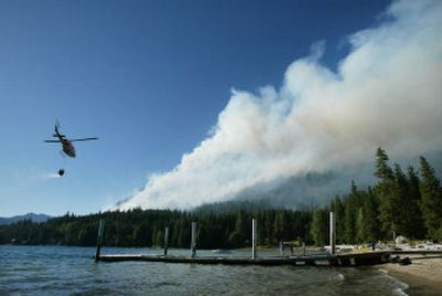 
After filling up its bucket in Lake Wenatchee, a helicopter heads off to help fight a wildfire Sunday in Chelan County. 
 (Associated Press / The Spokesman-Review)