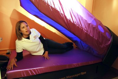 Charlotte Nemec, owner of the Planet Beach spa in Spokane Valley, demonstrates the massage machine at her business, Planet Beach. The shop offers automated spa services such as tanning, facials, sauna and this machine, which uses water to give a full massage to a fully clothed customer.  (Jesse Tinsley / The Spokesman-Review)