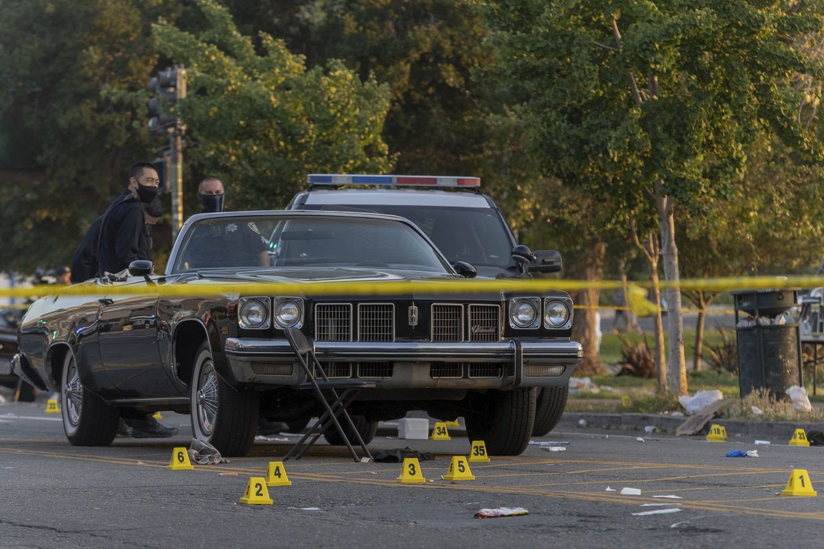 In this Saturday, June 19, 2021, photo, officers work the scene of a shooting in Oakland, Calif. A 22-year-old man was killed and five others were wounded in a shooting in Oakland near the city’s Juneteenth celebration, though it wasn