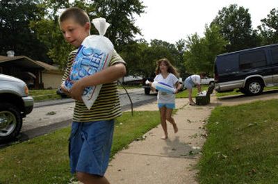 
Devon Paluczak, 11, and his sister Siera, 9, rush ice to their neighbors Thursday outside St. Louis, where half a million homes and businesses faced power outages amid high temperatures. 
 (Associated Press / The Spokesman-Review)