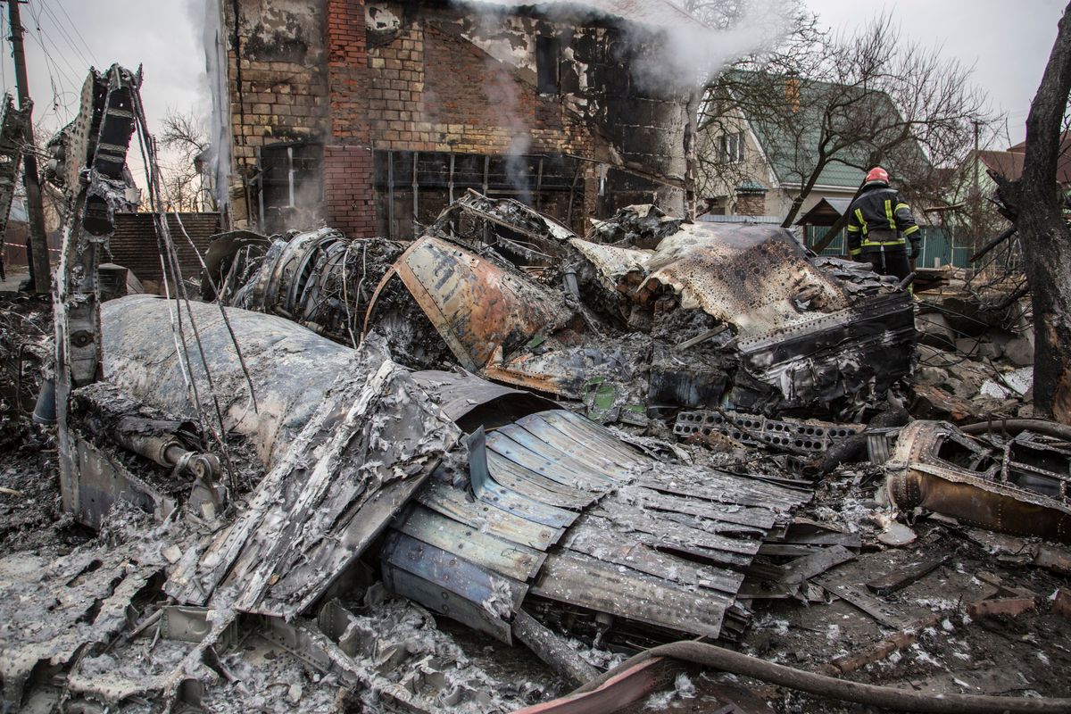 A Ukrainian firefighter walks between at fragments of a downed aircraft seen in in Kyiv, Ukraine, Friday, Feb. 25, 2022. It was unclear what aicraft crashed and what brought it down amid the Russian invasion in Ukraine Russia is pressing its invasion of Ukraine to the outskirts of the capital after unleashing airstrikes on cities and military bases and sending in troops and tanks from three sides.  (Oleksandr Ratushniak)