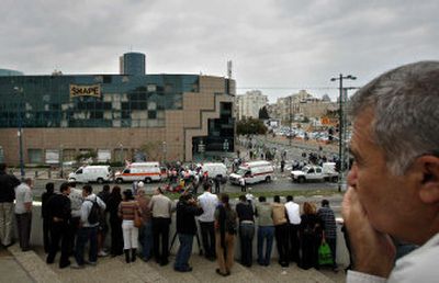 
Bystanders look on as rescue workers gather at the site of a suicide bomb attack in the Israeli coastal city of Netanya. 
 (Associated Press / The Spokesman-Review)