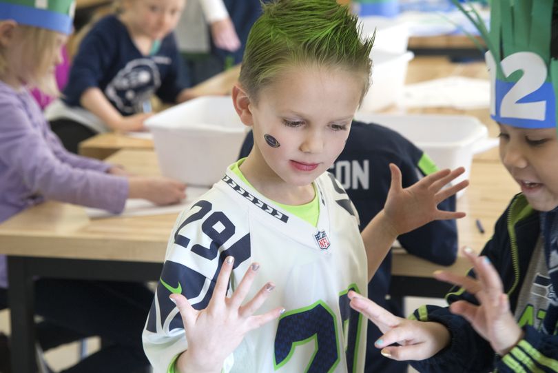 Kindergartner Wil Thomas, with green hair, compares Seahawks-themed fingernail polish with Jaelah Powers, right, during Thursday’s party. The school day marked the end of the semester.