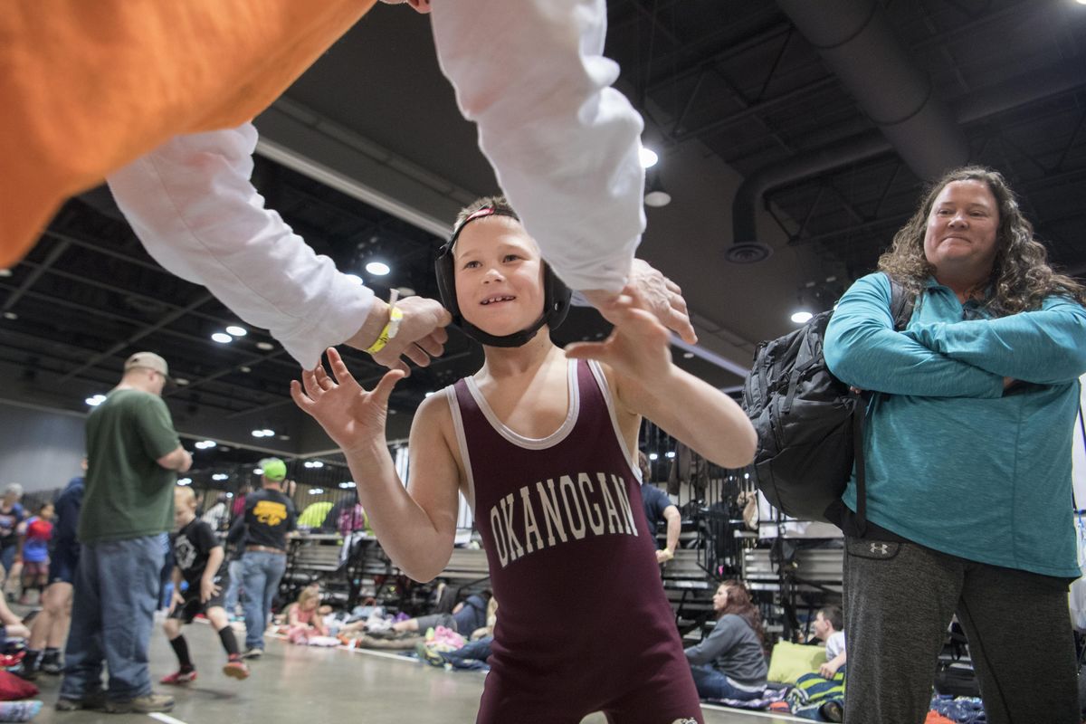 Jaxon Morgan, center, practices some of his wrestling moves on his dad, Dave, left, before going to his bout in the Spokane Convention Center, Saturday, April 7, 2018, during the Jason Crawford Memorial Tournament. Jaxon is in the 67-71 lbs weight class. More than 1,600 wrestlers signed up for the event aimed at wrestling clubs around the region. (Jesse Tinsley / The Spokesman-Review)