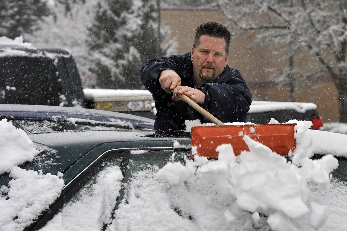 Gene Rayman of Manito Automotive Technicians brushes a layer of snow from a parking lot full of cars Wednesday. After 60-degree temperatures Tuesday, snow blanketed many parts of the area Wednesday. “I have to clean them off before I can work on them,” Rayman said. (Dan Pelle)